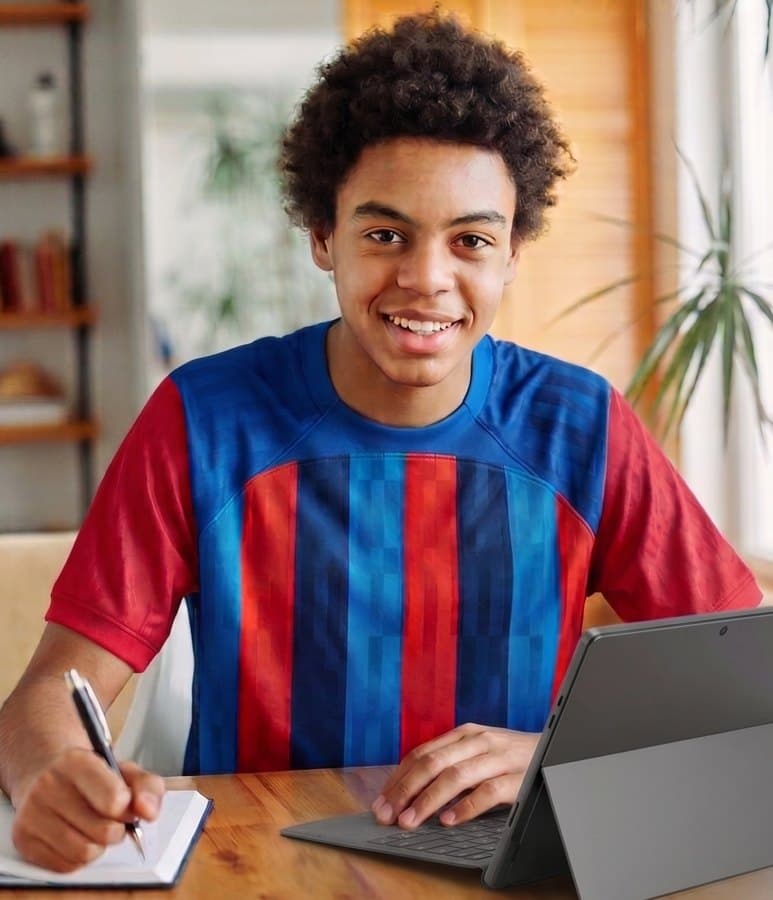 A secondary-school student smiling at his desk